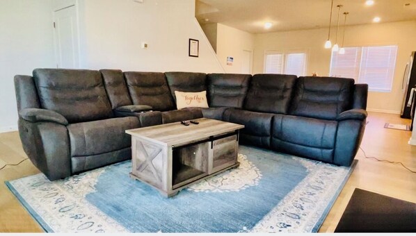 A sectional sofa with a wooden coffee table in a living room with a blue patterned rug. - Spacious 5-bedroom house with WiFi and AC in charming Winston-Salem (Winston-Salem)