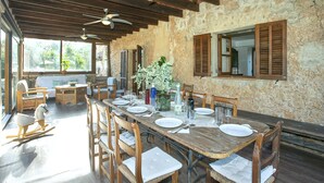 Comedor con una larga mesa de madera dispuesta para una comida, rodeada de sillas de madera con asientos acolchados.