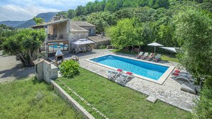 Una villa con piscina, mobiliario exterior y jardín.