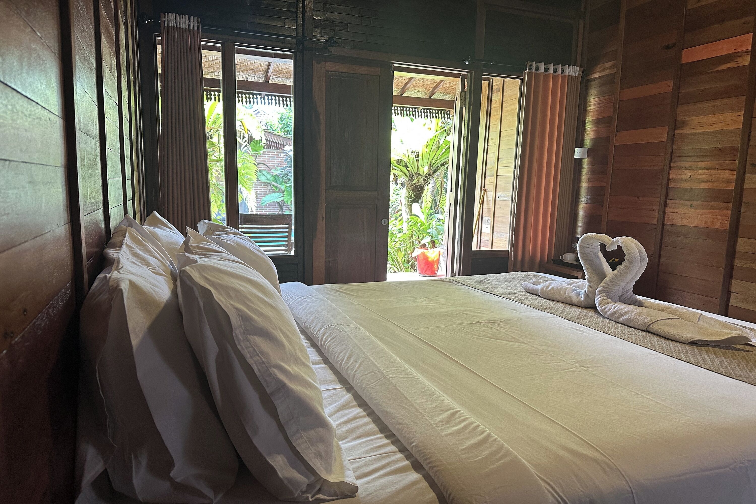 Una habitación con cama, cortinas y vistas a zonas verdes.