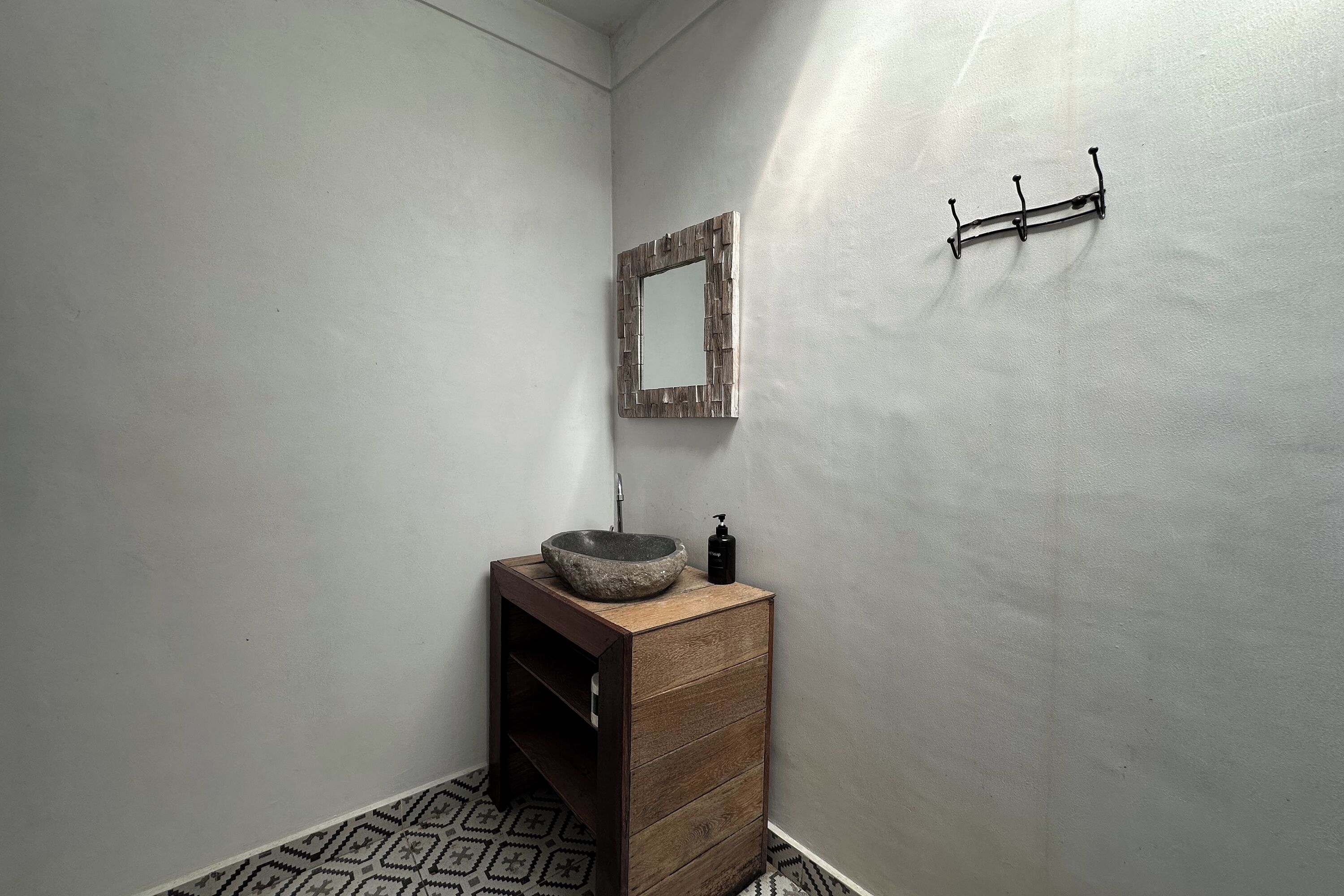 A bathroom with a wooden vanity, a stone sink, a mirror, and a towel rack.