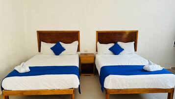 Two single beds with wooden headboards, white bedding, and blue accents. Each bed has a matching wooden nightstand.