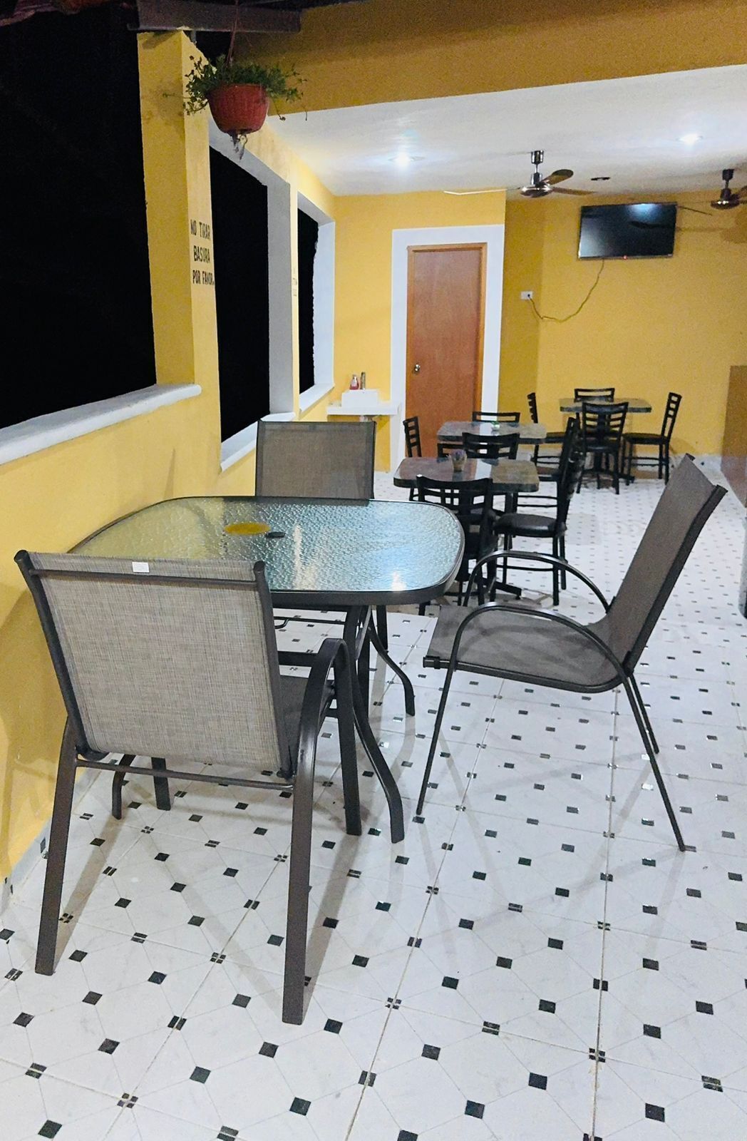 Un comedor con una mesa de vidrio, sillas de metal y piso de baldosas.