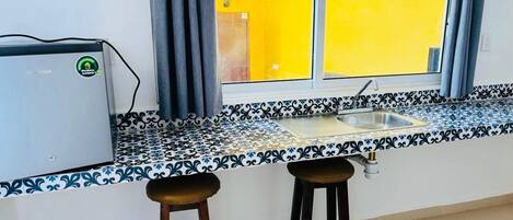 Una cocina con ventana, dos taburetes y un fregadero.