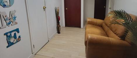 A hallway with a brown leather couch, a wooden door labeled "C2", and a wall with decorative letters and a small plant.