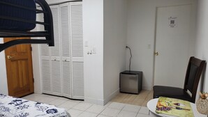 A room with a bunk bed, a small refrigerator, a table with a placemat, and a door with a QR code.
