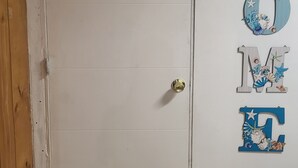 A white door with a 'C3' sign, and a wall with decorative letters spelling 'HOME' with seashells.