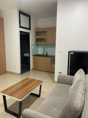 A modern kitchen with wooden cabinets, a built-in oven, and a black refrigerator. - Era Apartment Tran Thai Tong (Hanoi)