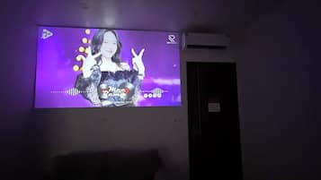 A projection screen displaying a music video with a person making a peace sign.