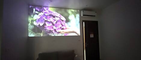 A projection of purple flowers on a wall in a dimly lit room with a sofa and a door.
