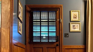 Una puerta de madera con un ventanal, un tapete estampado y cuadros en la pared.
