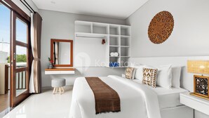 A modern bedroom with a large bed, built-in shelving, a mirror, and a decorative wall piece. - Cavara Villa by Kozystay - Ungasan (Ungasan)