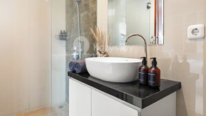 A modern bathroom with a large white sink, a handheld showerhead, and two bottles of hand lotion. - Cavara Villa by Kozystay - Ungasan (Ungasan)