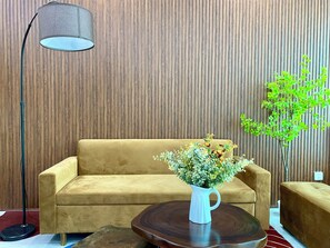 A room with a sofa, a coffee table, a floor lamp, and a potted plant.