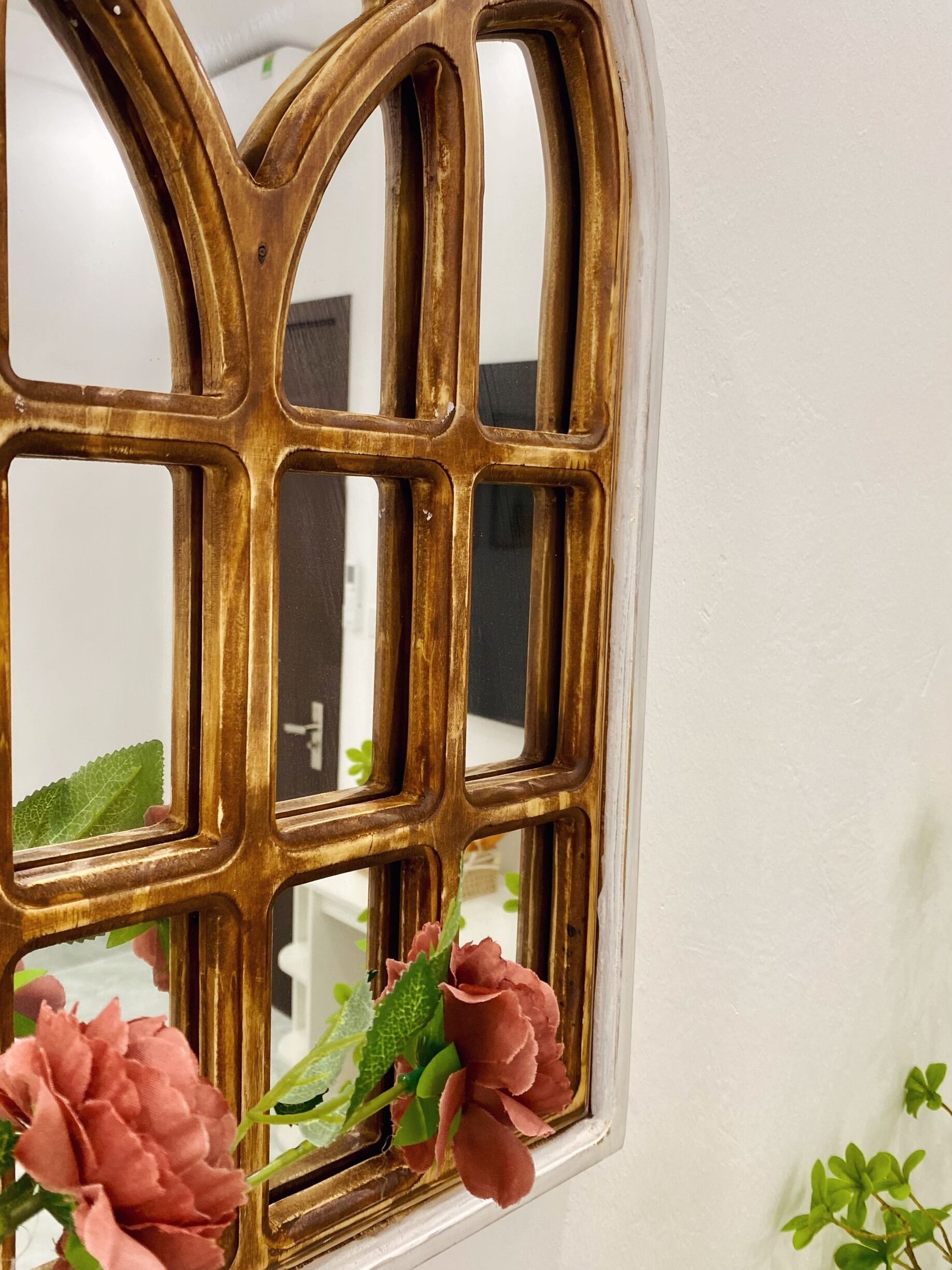A window with a decorative metal frame and a floral arrangement at the bottom.