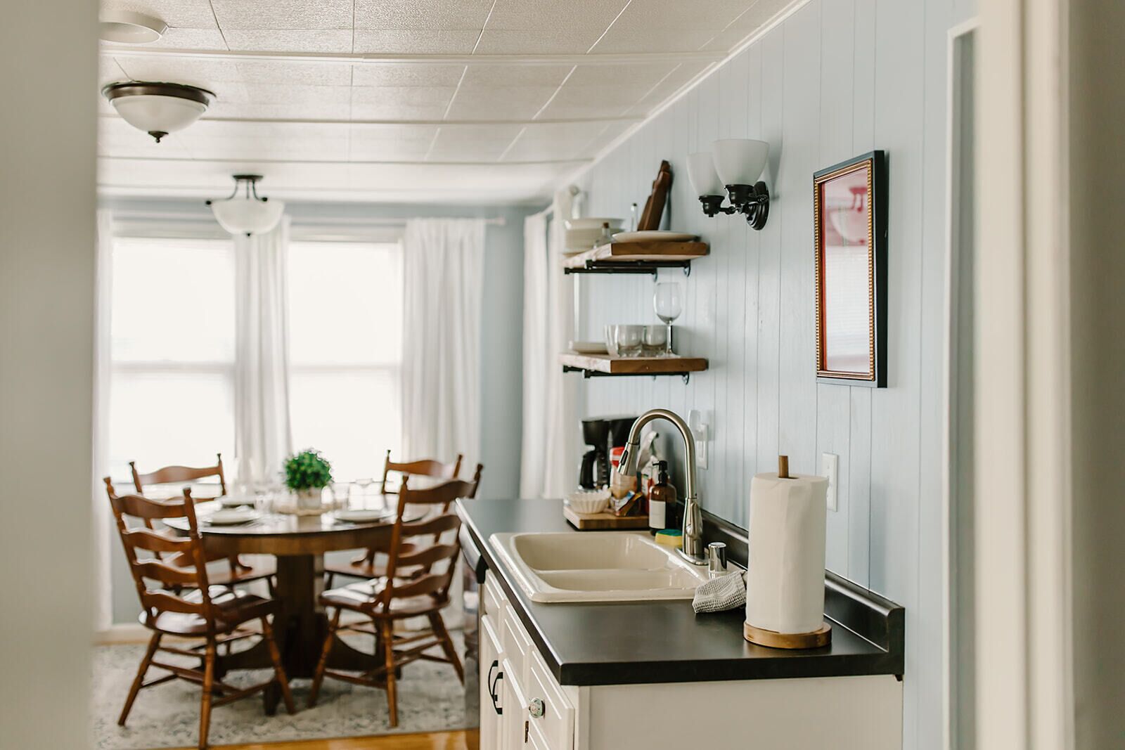 A kitchen with a dining table, chairs, a sink, and a countertop.