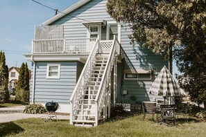 Une maison à deux étages avec un porche à l’avant, un escalier et du mobilier d’extérieur.