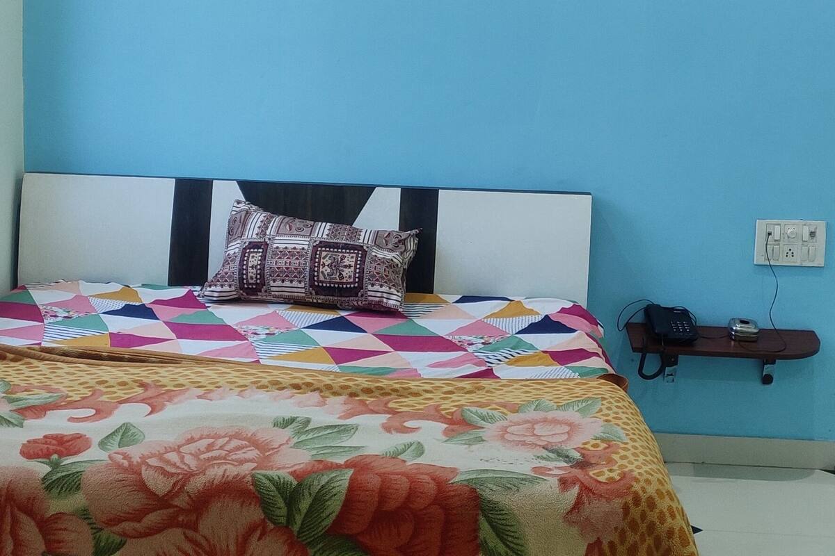 Ein Schlafzimmer mit Bett, Klimaanlage und einem kleinen Regal mit Telefon und Ladegerät.