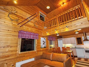 A cabin interior with a dining area, kitchen, and a cozy seating area.