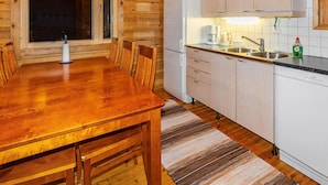A wooden interior with a dining table and chairs, a refrigerator, a sink, and cabinets. - Villa kunteus by Interhome (Raattama)