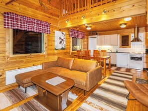 A cozy cabin interior with a sofa, a dining table, and a kitchen area.