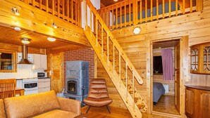 A cozy cabin interior with a wooden staircase, a fireplace, a sofa, and a dining area. - Villa kunteus by Interhome (Raattama)