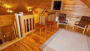A wooden cabin with a loft bedroom, wooden flooring, a window, and two leather chairs. - Villa kunteus by Interhome (Raattama)