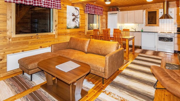 A cozy cabin interior with a wooden interior, a sofa, a dining table, and a kitchen area. - Villa kunteus by Interhome (Raattama)