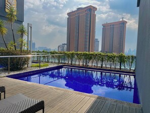 A rooftop pool with a view of high-rise buildings, surrounded by trees and a wooden deck. - Bintang Fairlane by Manhattan Group  (Kuala Lumpur)
