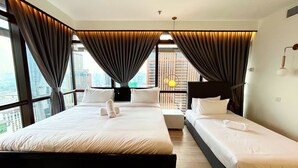 Een hotelkamer met twee bedden, grote ramen en gordijnen.