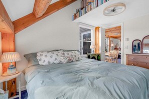 Un dormitorio con cama, mesita de noche, lámpara, cómoda y estantería.