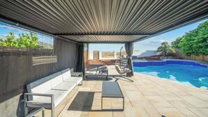 Ein überdachter Außenbereich mit Pool, Sitzgelegenheiten und Blick auf die Landschaft.