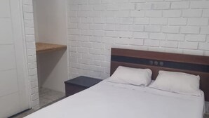 A bedroom with a bed, a nightstand, a wooden headboard, a white brick wall, and a tiled floor. - Hermosa casa en playa pulpos, cerca de las playas, comercial KM40 . (Punta Hermosa)