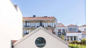 A modern house with a flat roof, a circular window, and a glass door leading to a balcony. - GuestReady - Silk Factory - B (Porto)