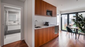 A modern kitchen with wooden cabinets, a built-in microwave, and a sink. - GuestReady - Silk Factory - B (Porto)