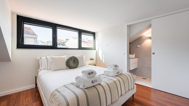 Quarto moderno com uma cama grande, janela com vista, closet espaçoso e banheiro.