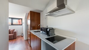 Cozinha moderna com fogão embutido, máquina de café e janela com vista para a paisagem urbana.