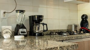 Una cucina attrezzata con frullatore, macchina per il caffè, tostapane e fornello a gas.
