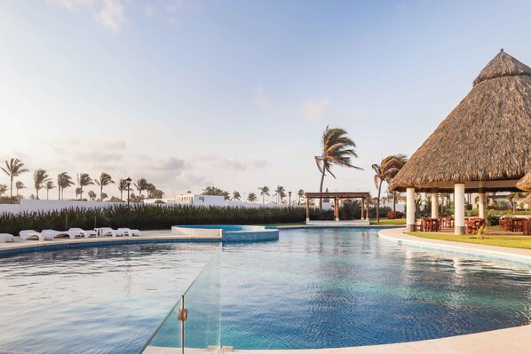 Una piscina al aire libre, sombrillas, tumbonas