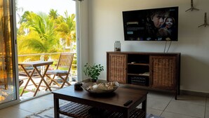 Un soggiorno con TV a parete, un tavolino in legno, un cesto in vimini e una pianta in vaso.