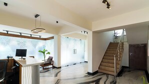 A spacious lobby with a marble floor, a reception desk, a staircase, and a large window. - The Keys By Unique Choice Hotels (Udaipur)