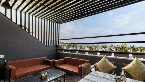 A rooftop terrace with a sofa, a table, and decorative pillows. - The Keys By Unique Choice Hotels (Udaipur)