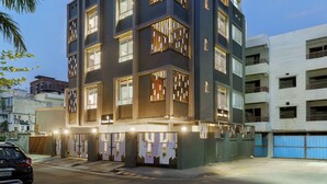 A multi-story hotel with a modern facade, large windows, and a parking area in front. - The Keys By Unique Choice Hotels (Udaipur)