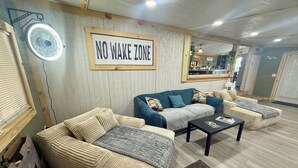 A cozy living room with a 'NO WAKE ZONE' sign, a blue sofa, a beige sofa, and a coffee table. - Charming 2-bedroom mobile home with WiFi and AC in Okeechobee (Okeechobee)