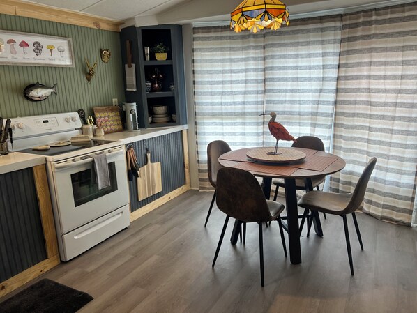 Una cocina con comedor, que incluye estufa, horno y una mesa con sillas.