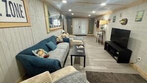 A living room with a sofa, coffee table, TV, and a framed sign on the wall. - Charming 2-bedroom mobile home with WiFi and AC in Okeechobee (Okeechobee)
