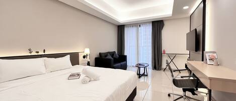 A modern hotel room with a large bed, a desk, a chair, a TV, and a window with curtains.