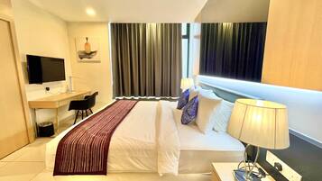 A hotel room with a bed, a desk, a TV, and a window with curtains.