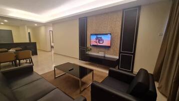 Una sala de estar moderna con un televisor de pantalla plana montado en la pared, una mesa de centro y sofás de cuero negro.