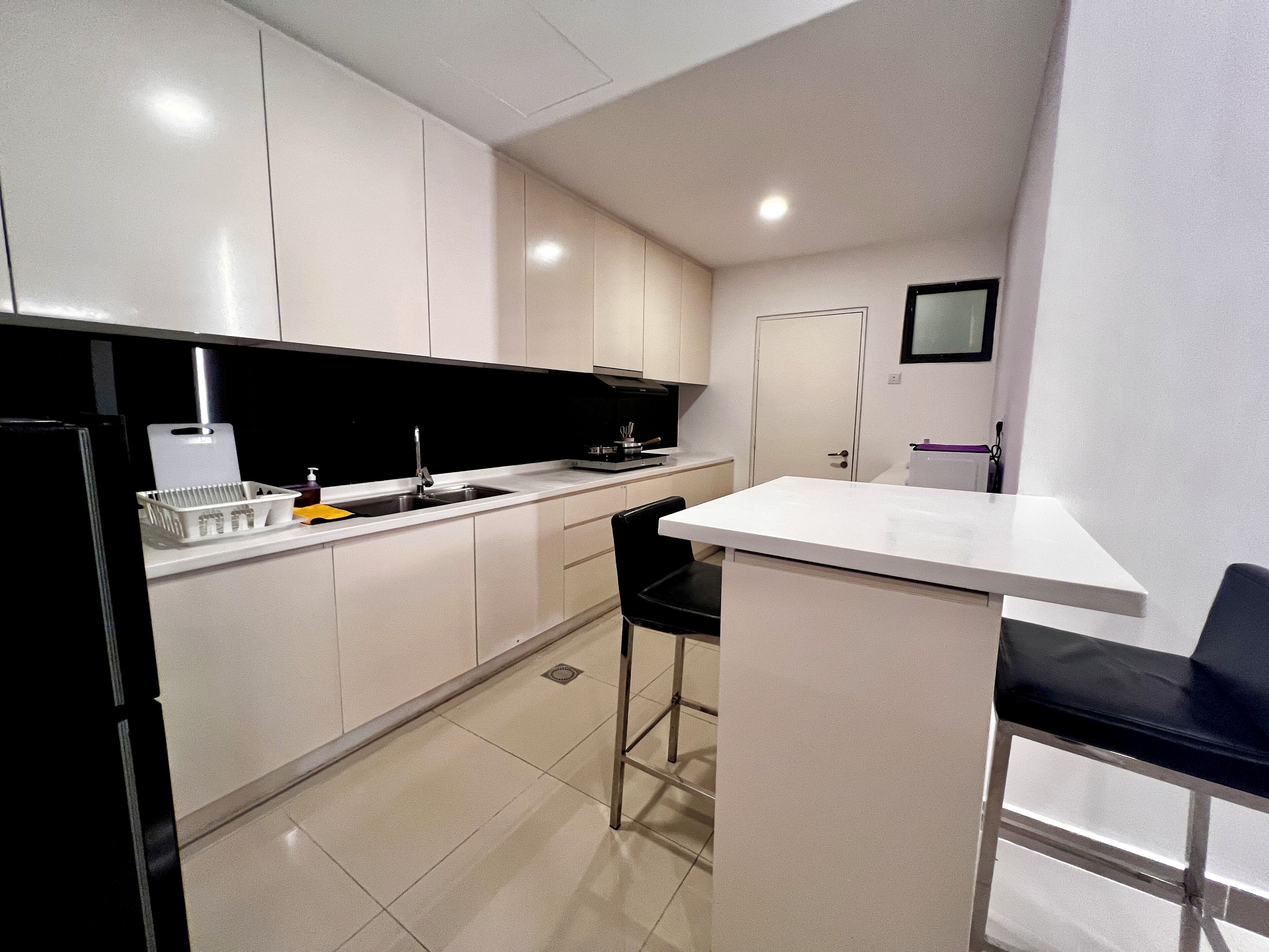 A modern kitchen with white cabinets, a black countertop, and a small bar area.